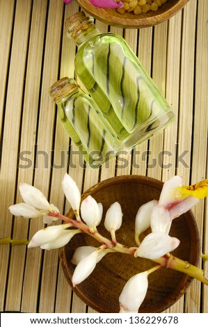 Wooden Bowl with tropical flower with massage oil on bamboo mat