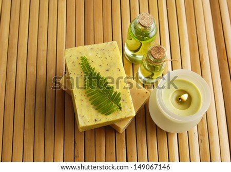 Bar of natural handmade soap with fern, candle, massage oil on wooden mat