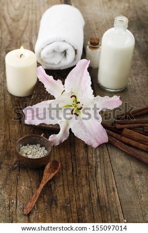 Aromatic spa set with salt in bowl, massage oil , lily flower on old wood
