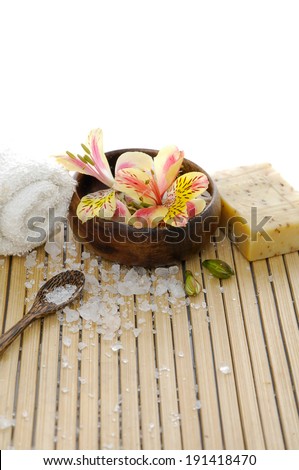 Orchid flower in bowl with soap with roller towel with salt on wooden