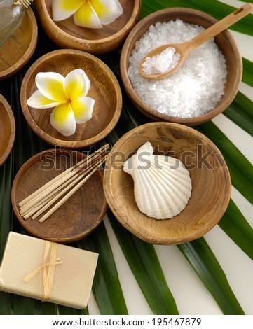 Wooden bowl of Yellow flower with pile of cinnamon ,shell , oil on green leaves