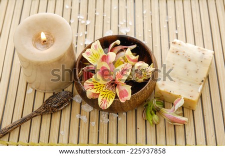 orchid flower in wooden bowl with soap, candle on mat