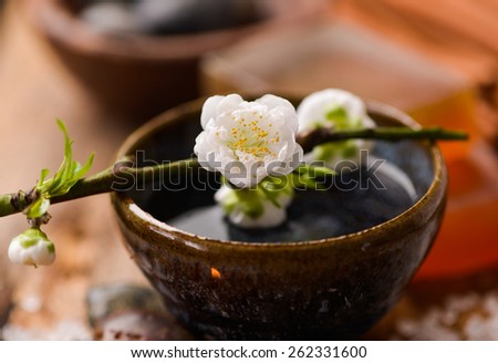 Cherry flower with pile of salt ,soap ,candle, oil on old wooden board