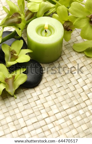 Spa resort composition - burning candles, orchid flowers and zen stones on straw mat