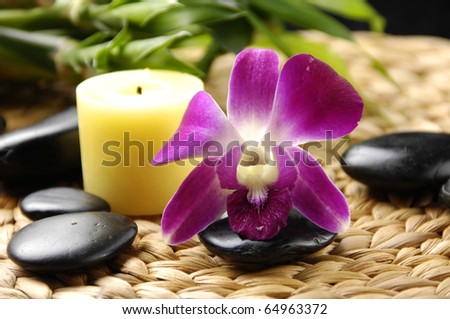 Spa resort composition - candles, orchid flowers, zen stones on woven mat