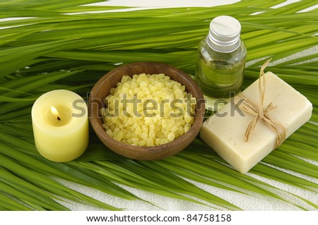 bath salts in bowl with yellow orchid and massage oil with soap on green palm