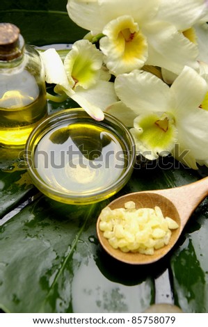 Sea salt bath in spoon with orchid and massage oil on monstera leaf
