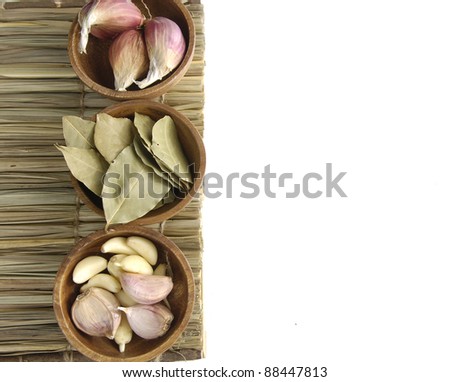 Dry bay leaf with garlic and garlic heads in a wooden bowl