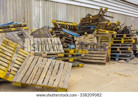 Old Stacked wooden pallets are lumber near a factory. dilapidated wood pallets background.