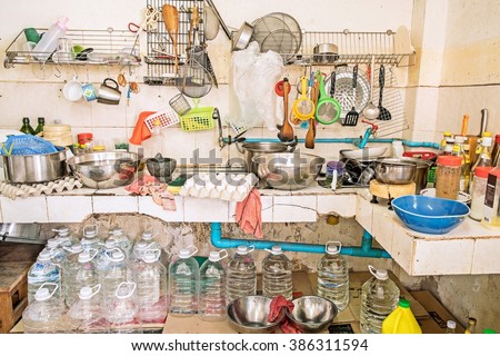 Untidy Kitchenware ; Pile of dirty dishes in sink and gallon water under the counter in the kitchen