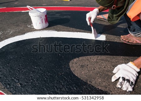 hand painting Road car speed limit and anti slip out of the lane.\
Road worker painting white color line with paint brush on the street surface