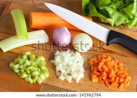 Ceramic knife with soffritto on wooden chopping board