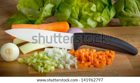 Ceramic knife with soffritto on wooden chopping board