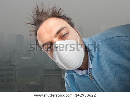 Young boy with mask respiratory protection near industrial city