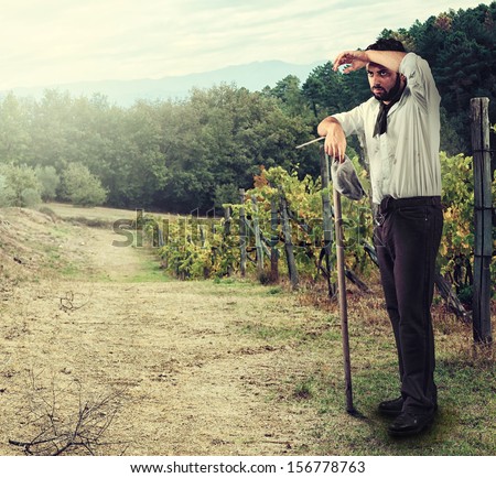 Tired Farmer in the vineyard leaning on the hoe