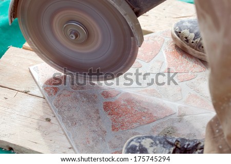 A man cutting a floor tiles with a grinder.