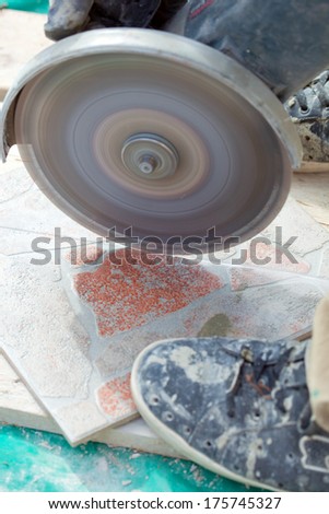 A man cutting a floor tiles with a grinder.