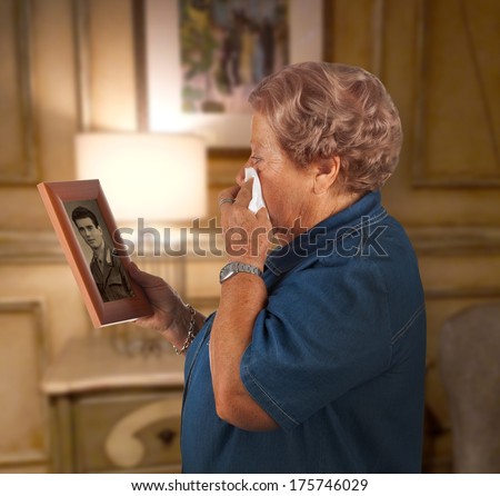Old lady crying watching a photo of a deceased person.