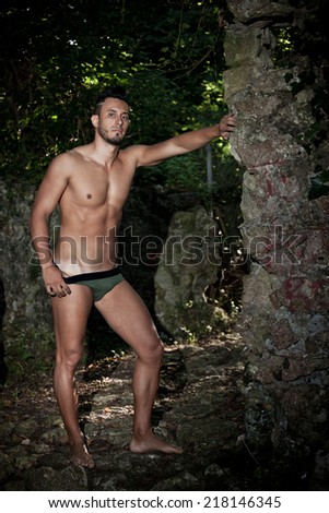 Handsome muscular man in briefs among the vegetation