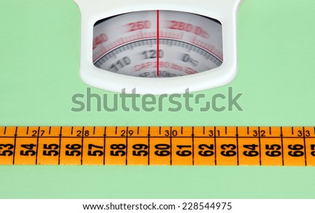 Bathroom scale with a measuring tape, weight loss concept.