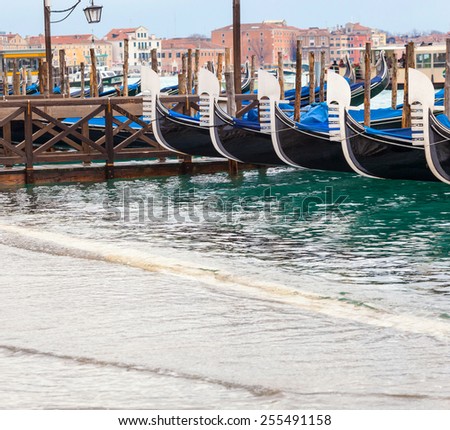 ypical Venetian gondolas with high tide that causes the famous event of high water in Venice, Italy.
