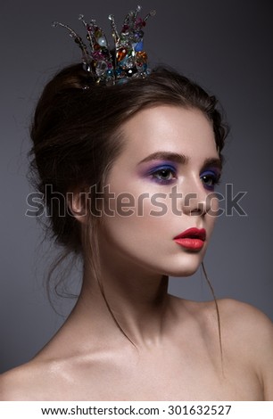 young woman with violet make-up and crown in studio