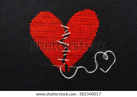 Broken heart, embroidered with red thread on black fabric. Heart sewn with white thread.