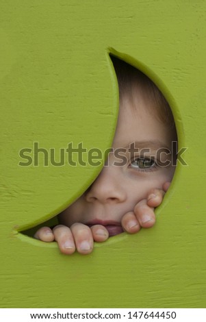 Little boy peeking out of the window of his tree house.