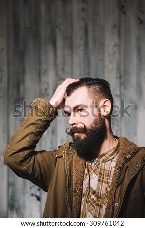Bearded man with great mustaches touches his hair.