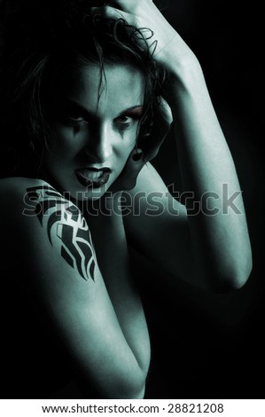 Dark portrait of young woman with tattoo and dramatic makeup