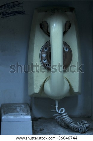 Old rotary phone in a small confined and dirty setting.