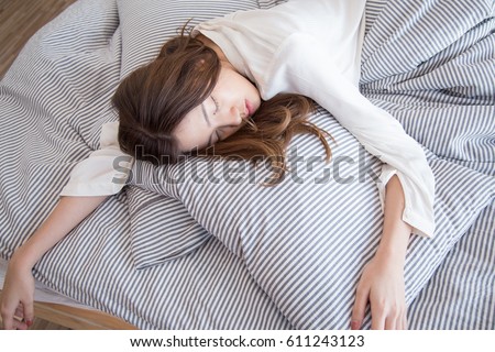 Young beautiful Asian lazy woman sleeping on the bed in vintage cozy bedroom at the morning