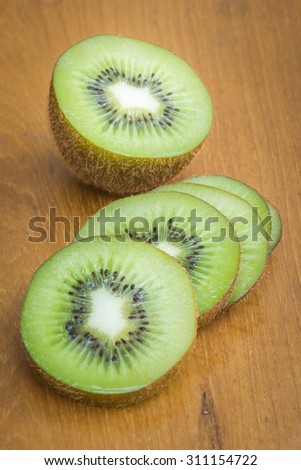 Kiwi fruit cut into pieces on a wooden background.