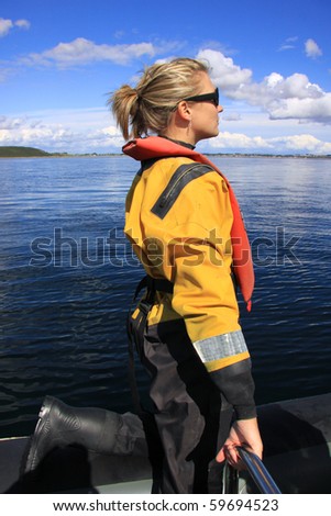 Attractive blonde girl at sea wearing a dry suit and life jacket