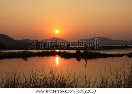 African lake at sunrise with the light reflecting off the calm water