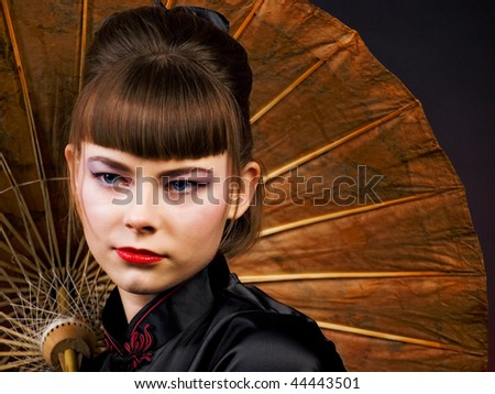 portrait of a girl with eastern makeup on background of Chinese parasol