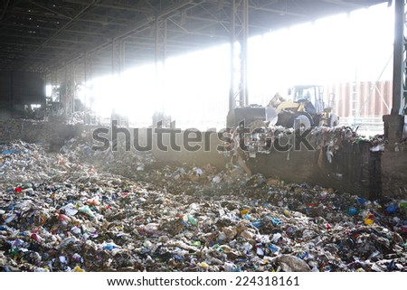 Bulldozer working on mountain of garbage in landfill