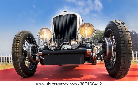 Front lower angle view of an unknown old-timer retro vintage sports car under blue sky