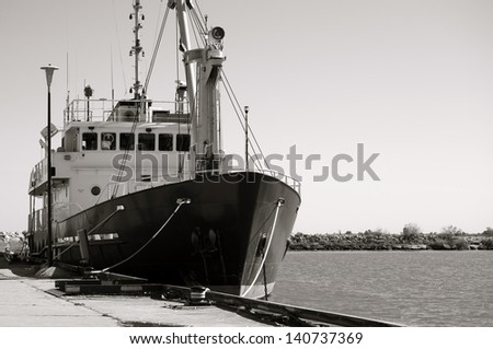 Black and white image of a small research vessel anchored at the pier.