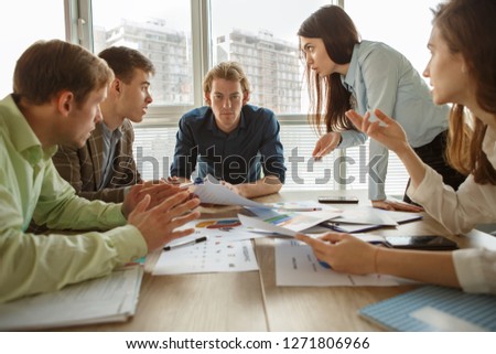 Front view of angry male worker sitting in middle of table and looking at camera. Leader of company tired of arguing and debating of colleagues on conference. Concept of stress and irritation.