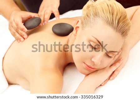 Getting stone massage. Beautiful relaxed woman getting stone therapy massage at the SPA salon