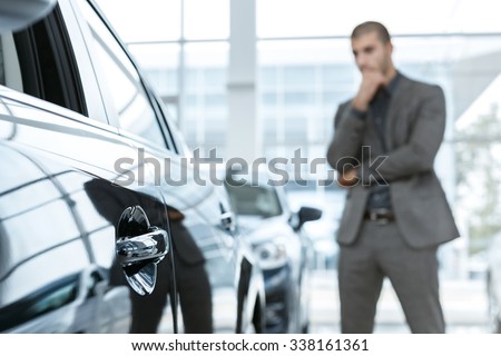 Hard choice. Selective focus on a car, man choosing car on the background