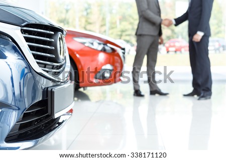 Closing the deal. Selective focus on the car customer shaking hands with dealer on the background