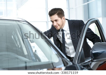 Taking a look. Half length portrait of a smiling businessman looking inside the car through the open door