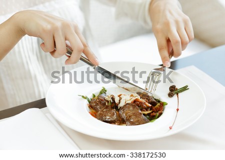 Healthy is delicious. Close up shot of a woman eating meat dish in a restaurant for lunch