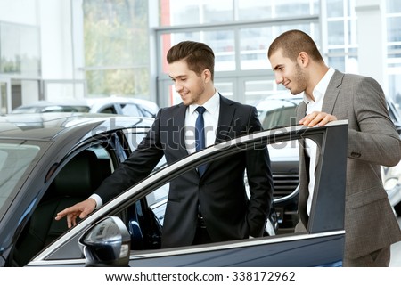 Take a look inside. Car salon manager inviting young businessman client to take look inside the car