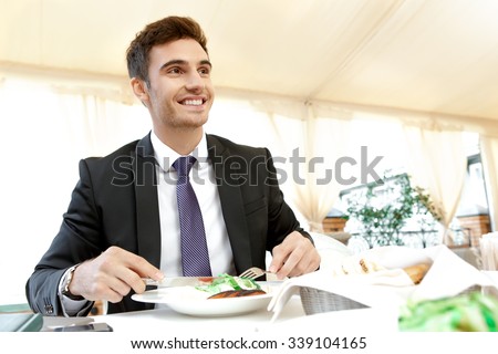 Meal on schedule. Handsome businessman having lunch by himself in an outdoor restaurant
