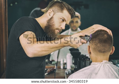Getting groomed. Shot of a handsome bearded barber giving a haircut to his client using trimmer