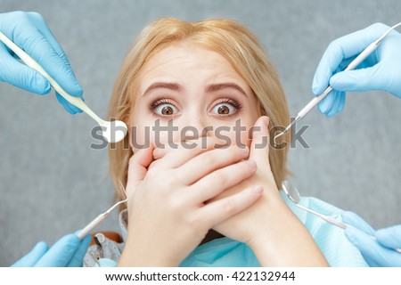 Her nightmare! Closeup shot of a terrified female covering her mouth with both hands at the dentist appointment