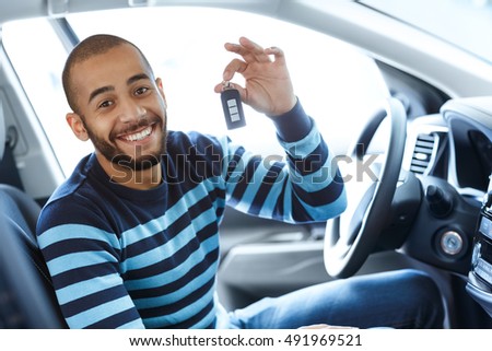 His dream day. Portrait of a handsome African man smiling excitedly while sitting in his newly bought car showing car keys to the viewer